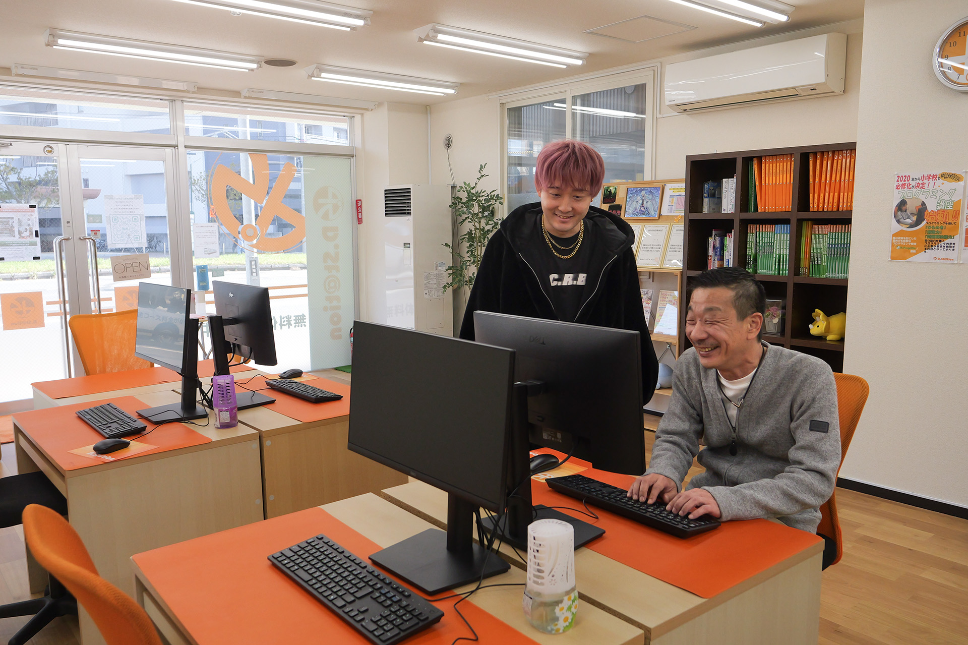 講師が生徒と隣り合い、笑顔でパソコンのディスプレイを眺めている様子